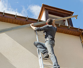 Man installing gutters on house