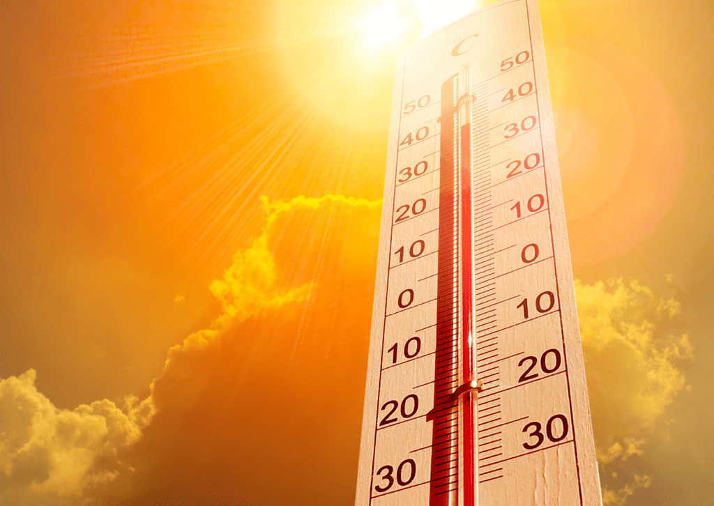 A thermometer reading high temperatures under the blazing sun and dramatic orange sky with clouds, indicating intense heat.