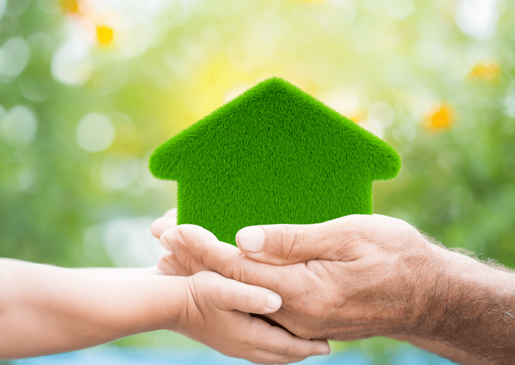 The hands of an adult and a child holding a house model with a grass texture, symbolize an eco-friendly living house.