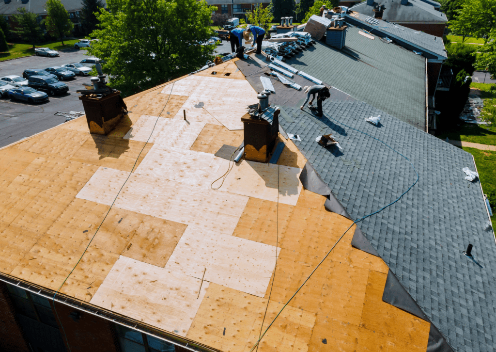 Workers installing new shingles on a roof, showcasing top-tier roofing solutions with part of the roof already completed.