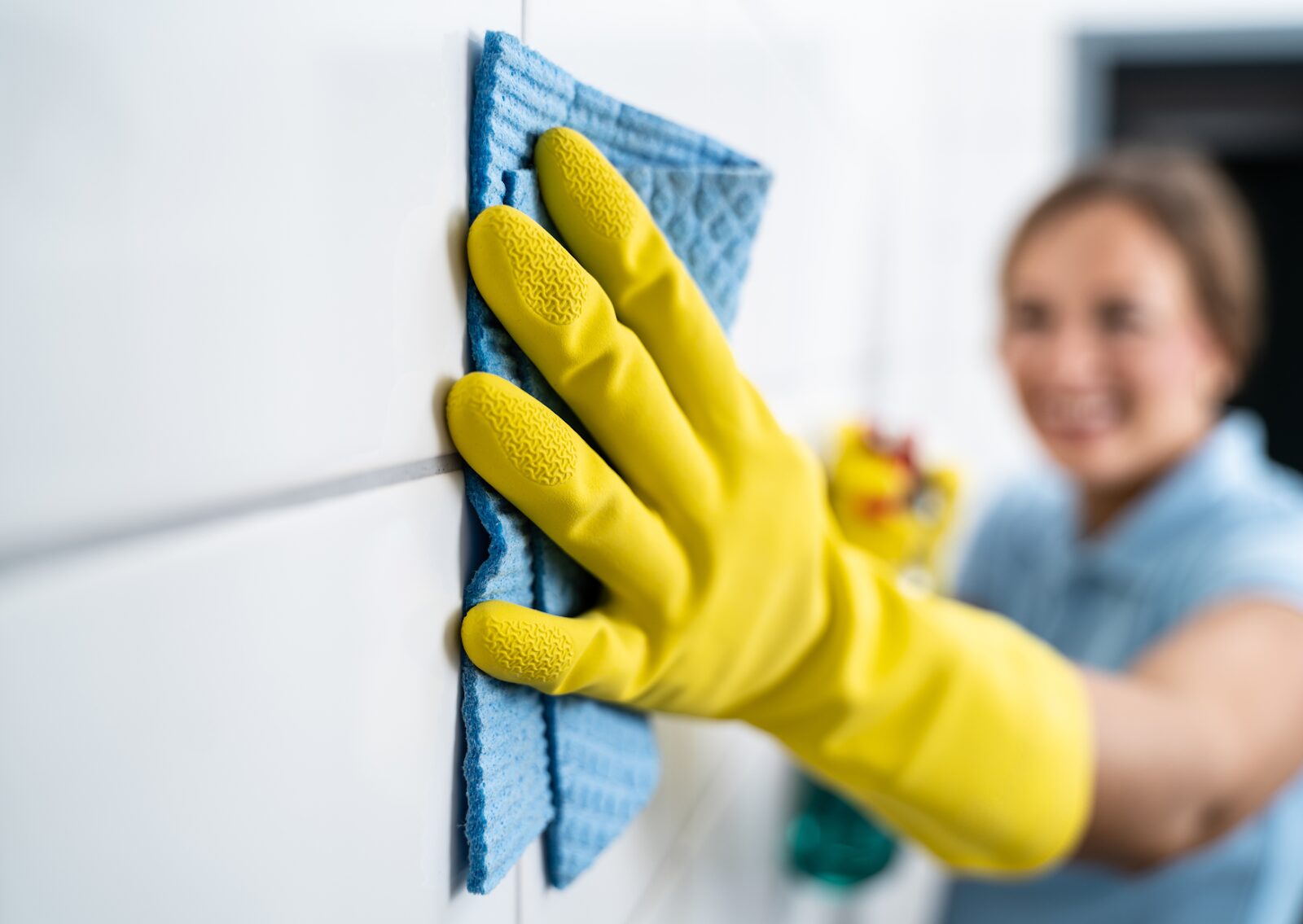 Preparing to paint color walls: A person in yellow gloves cleans the surface with a blue cloth for a smooth finish.