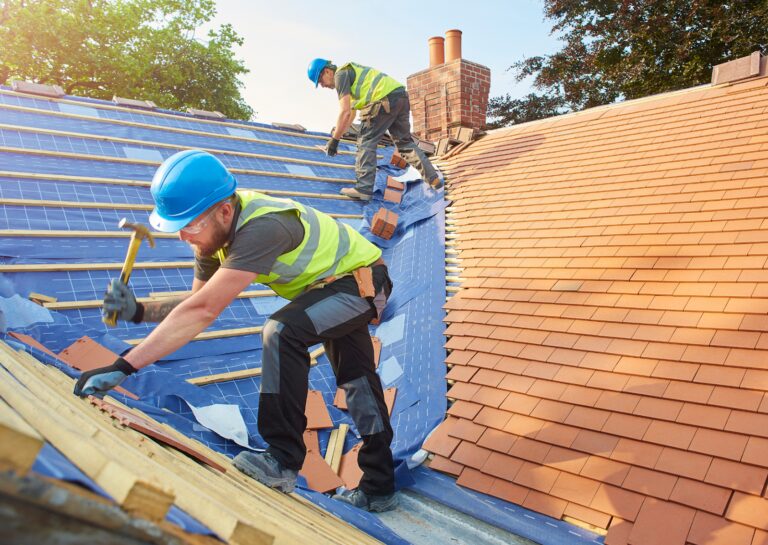 Roofers from a local roofing company installing new tiles on a roof, showcasing professional craftsmanship and teamwork.