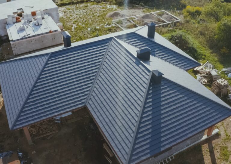 A newly installed roof with blue shingles and multiple chimneys, showcasing a completed roof repair in a construction area.