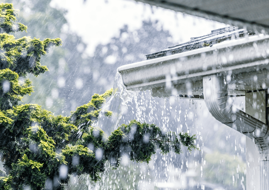 Heavy rain overflowing from a clogged gutter, highlighting the importance of proper gutter maintenance and repairs.