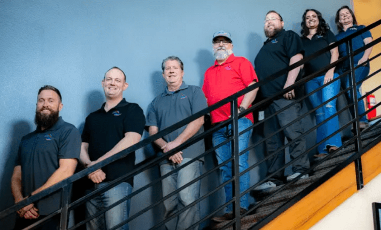 The team of M&E Painting & Roofing standing on a staircase, representing a premier roofing company in Colorado.