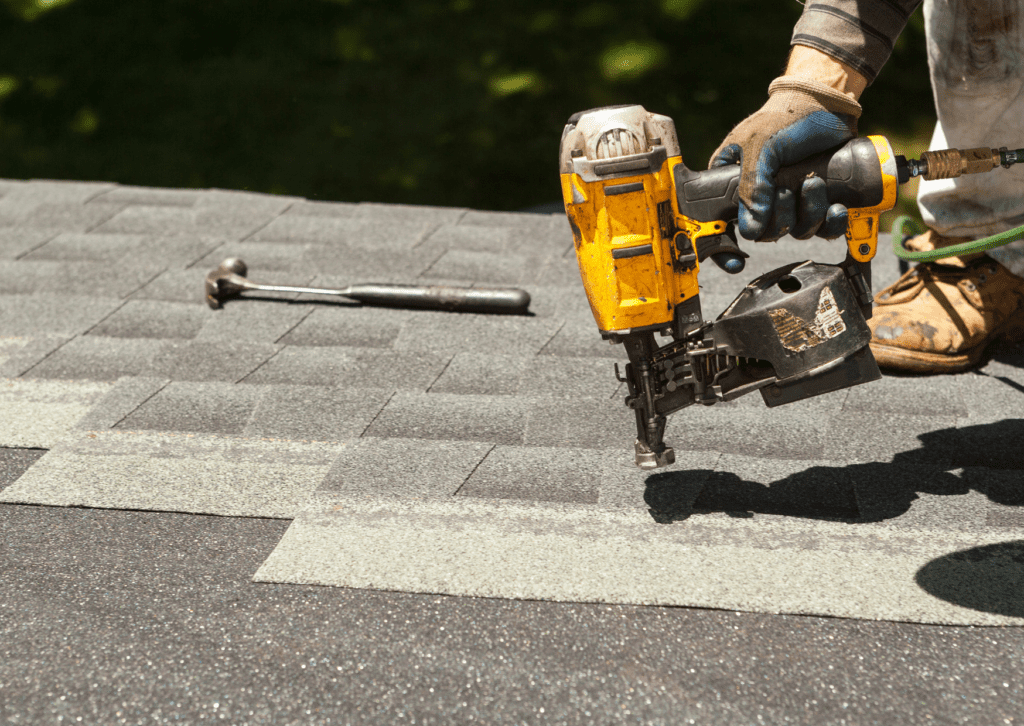 Roofing contractor using a nail gun to install asphalt shingles on a residential roof, emphasizing precision and durability.