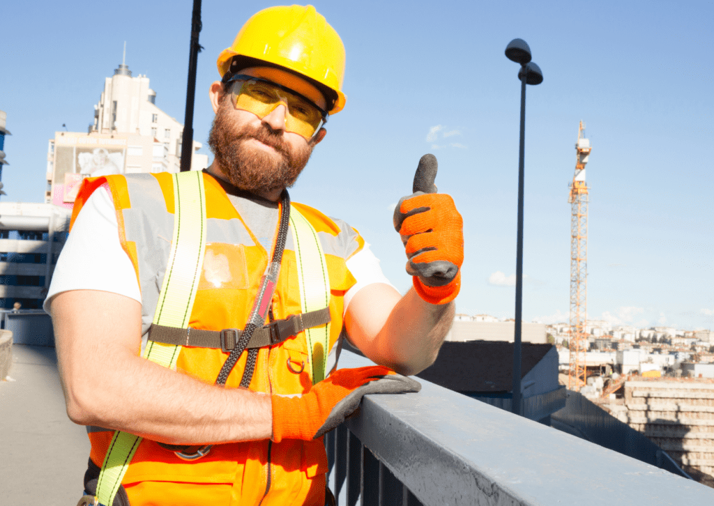 Construction workers in safety gear give a thumbs-up on a building site, emphasizing safety and job satisfaction.