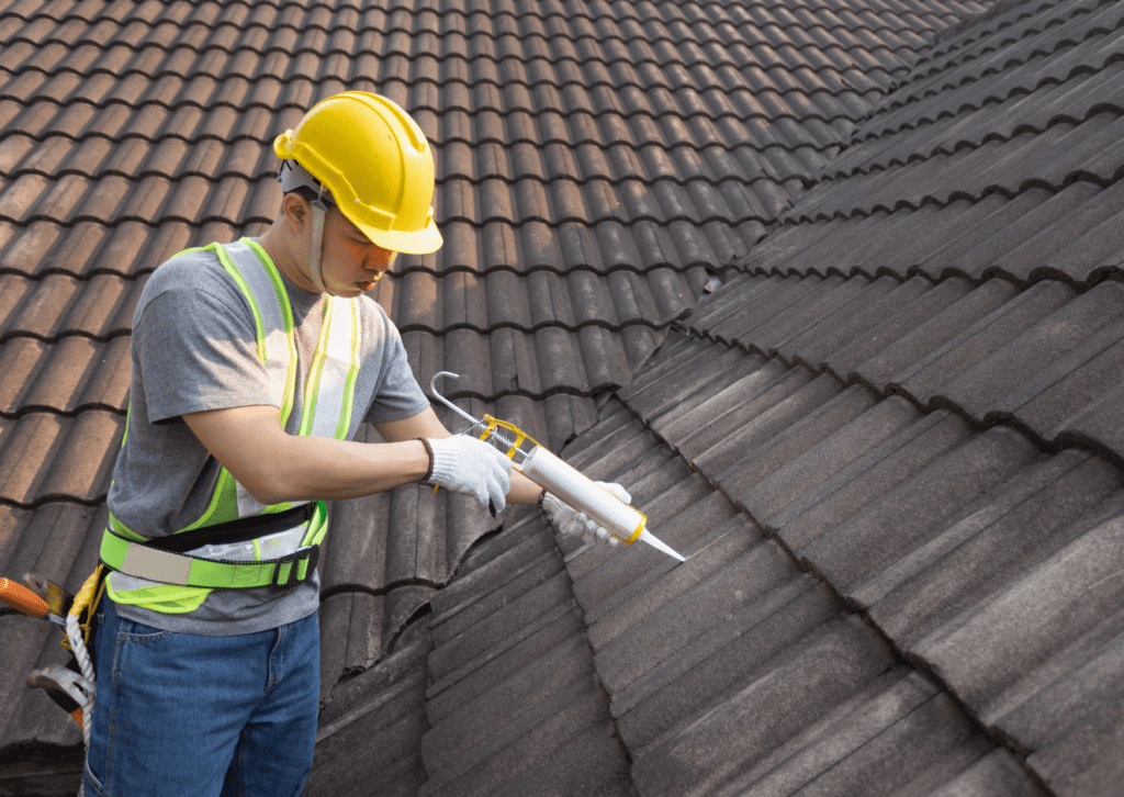 Worker applying sealant to roof tiles, ensuring proper waterproofing and preventing leaks during roof maintenance.