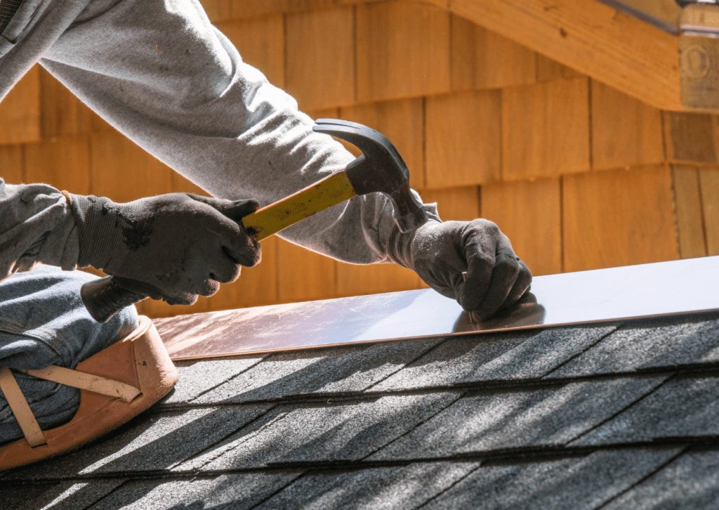 Worker hammering on shingles, illustrating professional roof repair solutions.