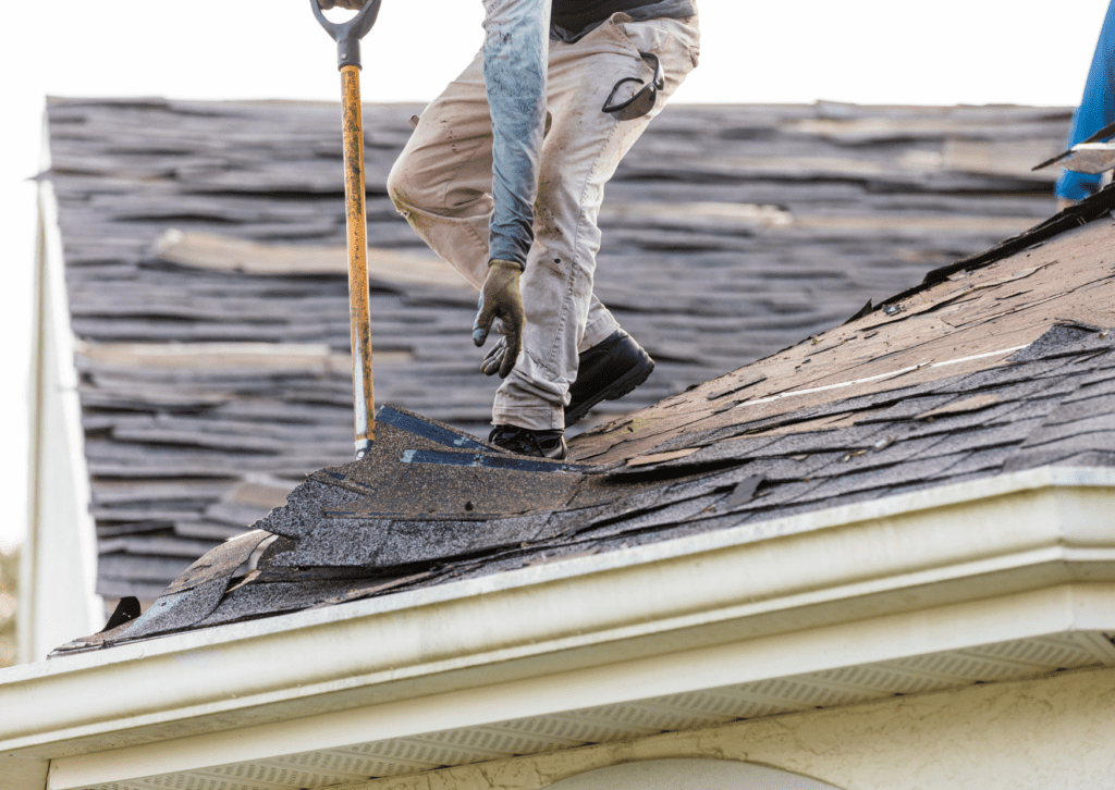 Worker removing old shingles during a roof repair project, showcasing effective roof repair solutions.