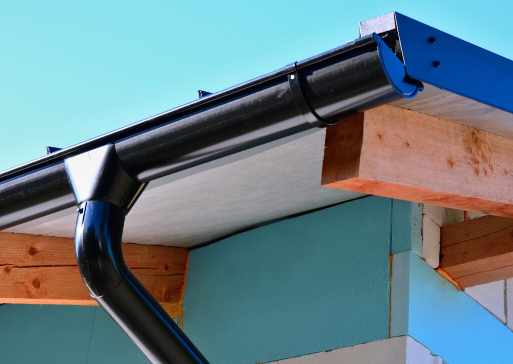 A black gutter system is installed on a modern home, providing efficient water drainage from the roof.