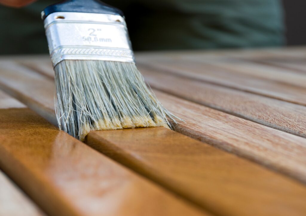 Brush applying the best wood paint on wooden slats for a smooth finish.