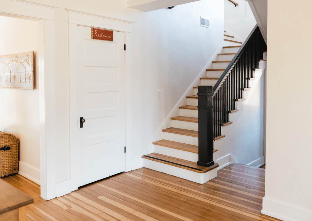 Entryway with wooden floors and stairs featuring black railings and wood steps, showcasing a modern interior.