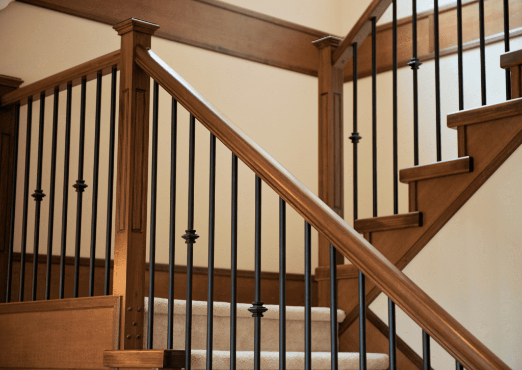 Wooden staircase with black iron railings and carpeted steps, showcasing a classic and elegant home interior design.