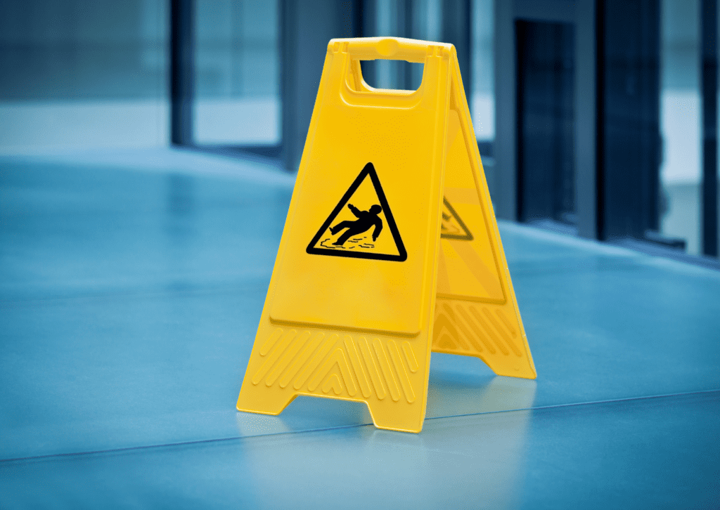 Yellow caution wet floor sign on a blue surface, indicating a slippery area and promoting safety to prevent accidents.