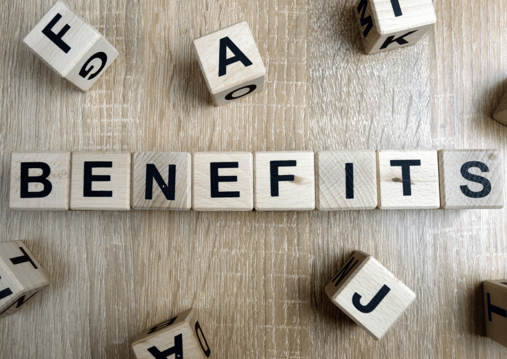 Wooden blocks spelling 'BENEFITS' on a table, with scattered letter blocks around.