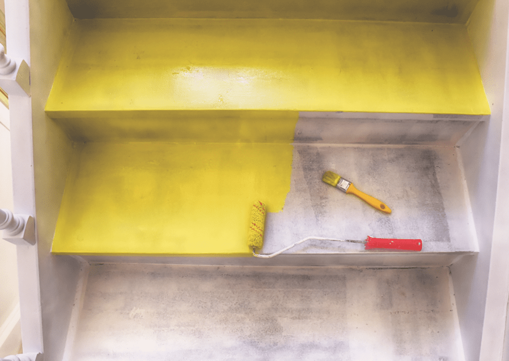 The staircase is painted yellow with a roller and brush, highlighting step-by-step paint for the stairs project in progress.