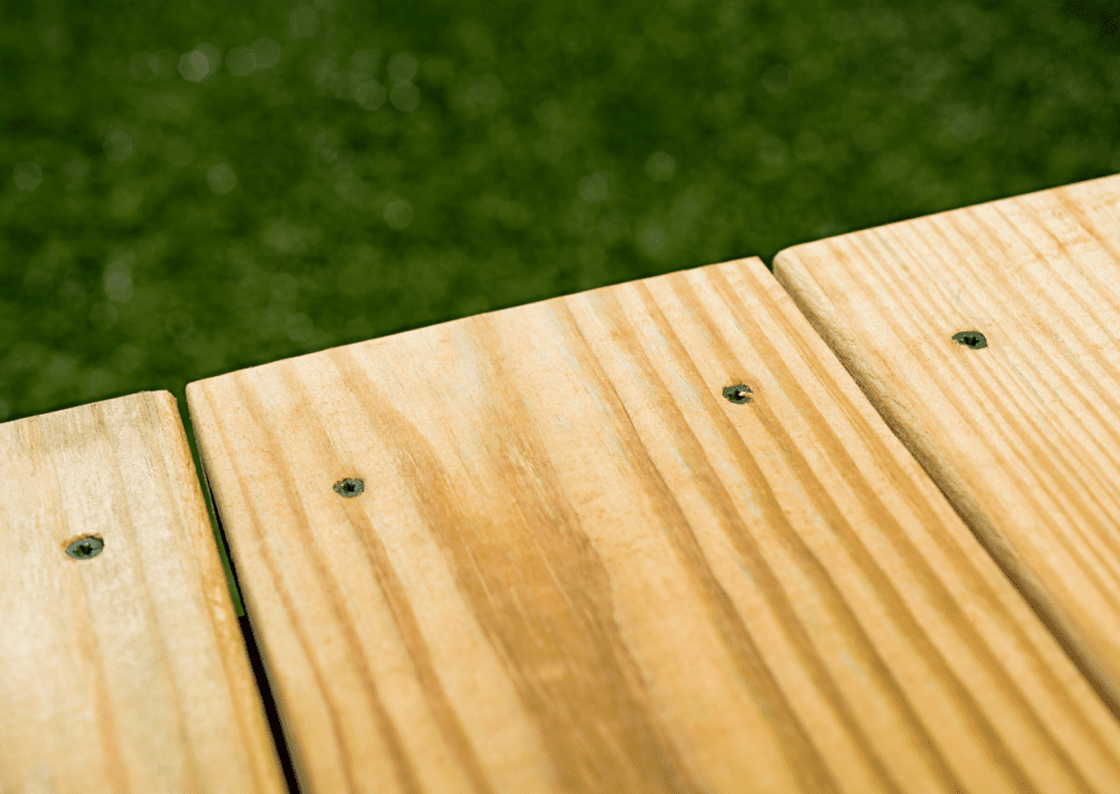 Close-up view of wet-treated wood decking, showcasing natural grain patterns and screws - can you paint wet-treated wood?