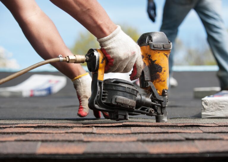 A roofer using a nail gun to secure shingles during a roof leak repair, ensuring a durable and weatherproof fix.