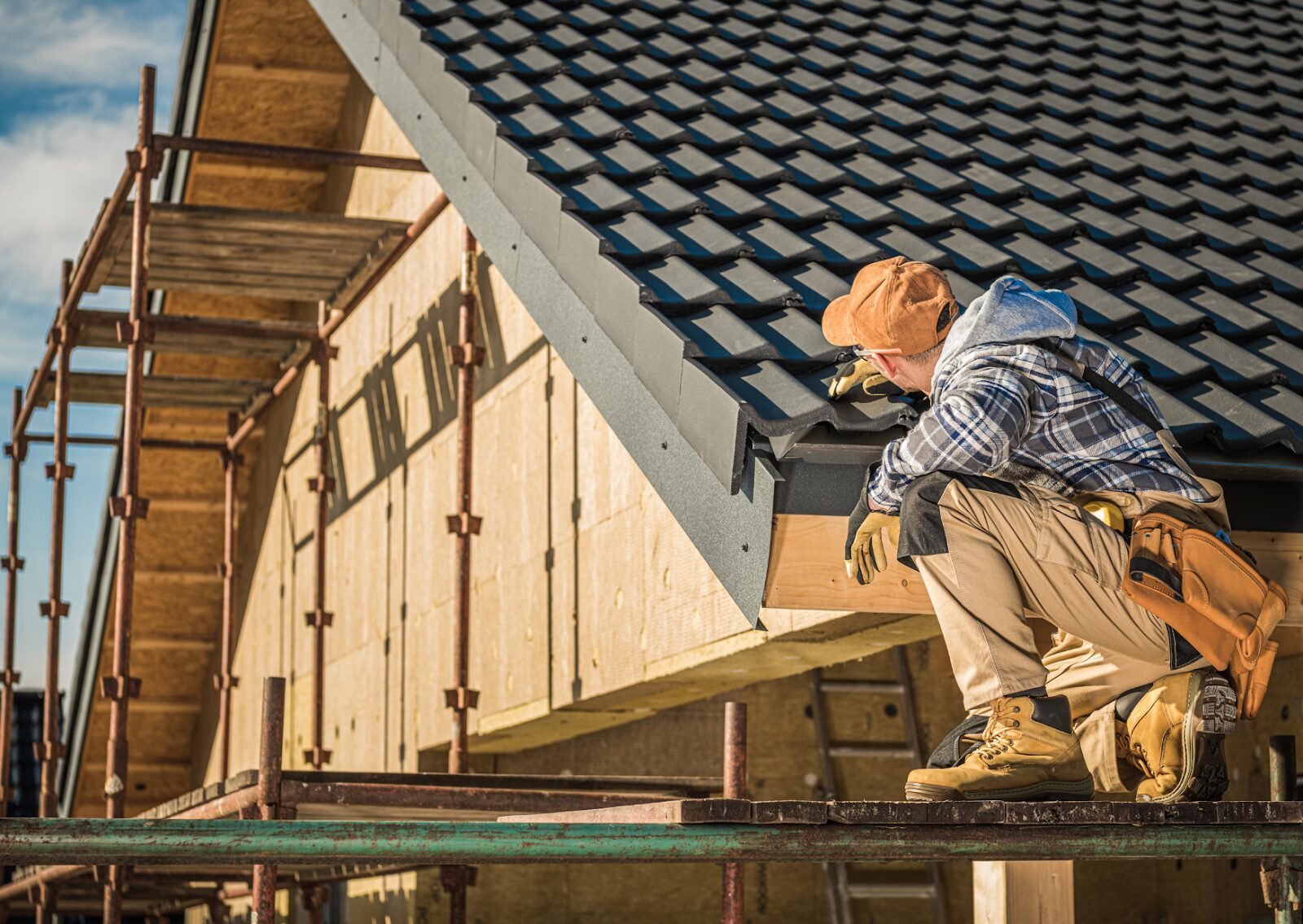 Construction worker inspecting tile installation during roof repair for homes on a new residential build.