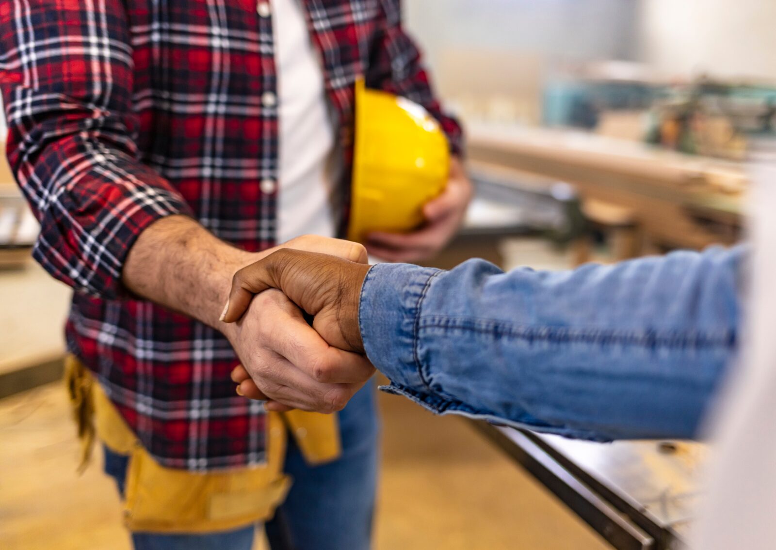 Close-up of two people shaking hands, symbolizing agreement or partnership in a construction setting.
